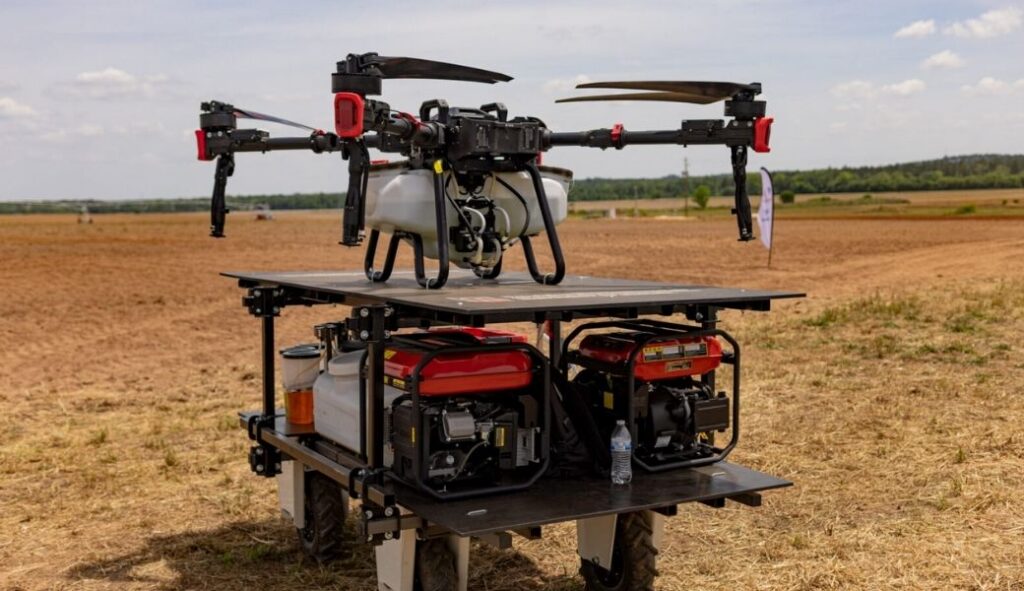 A drone sits on a charging station in an agricultural field.